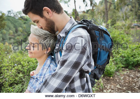 Side view of man kissing woman on head in forest