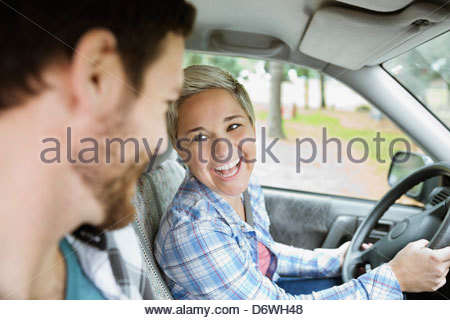 Cheerful young woman looking at man while driving car