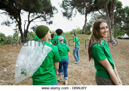 Happy young female environmentalist looking away with volunteers walking in park