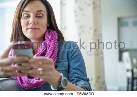 Beautiful mature woman text messaging at home
