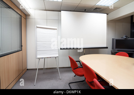 Blank projector screen and flip chart at the meeting room Stock Photo