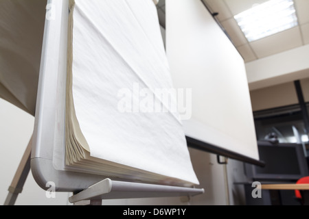 Blank projector screen and flip chart at the office Stock Photo