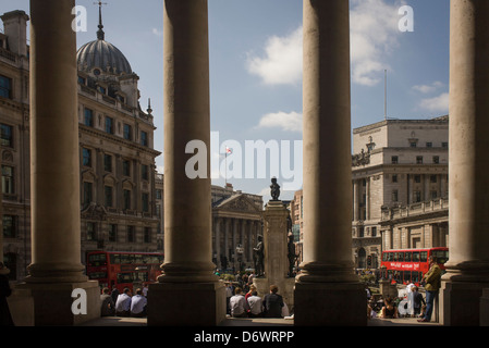 Lunchtime spring crowds enjoy warm weather beneath the pillars at Cornhill Exchange in the City of London. Stock Photo