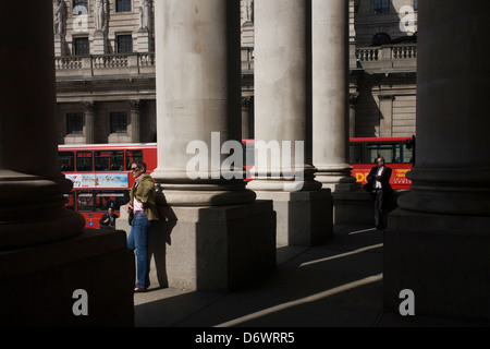 Lunchtime spring crowds enjoy warm weather beneath the pillars at Cornhill Exchange in the City of London. Stock Photo