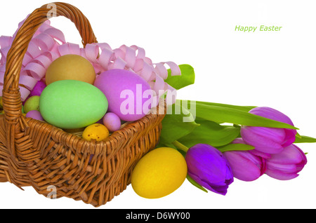 Wicker basket with colored eggs and flowers. Stock Photo