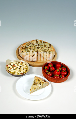 Italian green olive, Onion and Rosemary Focaccia, Feta Cheese and Cherry Tomatoes against a grey and white background. Stock Photo