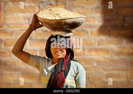 Street scene - portrait of a india hindu smiling woman carrying a basket on her head, Jaisalmer, India Stock Photo