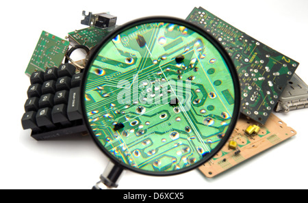 Concept photo showing digital computer parts discarded in garbage pile examined with maginfying glass Stock Photo