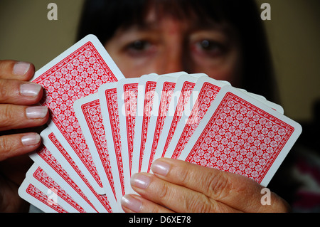 Woman choosing a card to play out of hand, England, UK, Western Europe. Stock Photo
