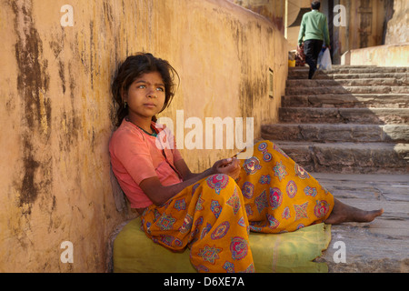 Portrait of poor young india girl child siting on the stairway to Amber Fort, Jaipur, India Stock Photo
