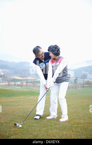 a man teaching his wife how to play golf Stock Photo
