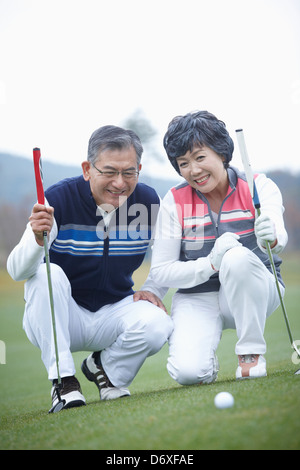 a couple looking at a golf ball on the grass Stock Photo