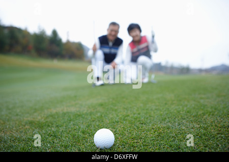 a couple watching the golf ball rolling on the grass Stock Photo