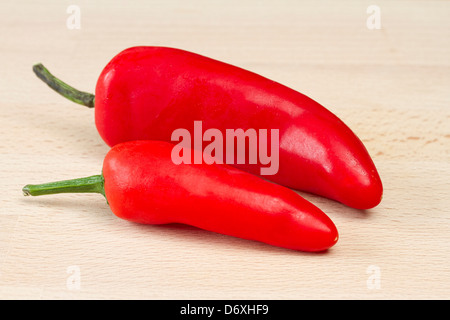Two red chillis on wooden chopping board Stock Photo