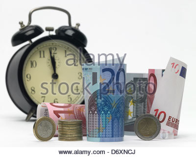 5,10 and 20 Euro notes rolled up standing and lying with alarm clock and euro coins
