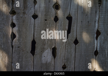 A detail of a well worn wooden barn door with unusual shaped holes in the wood. Stock Photo