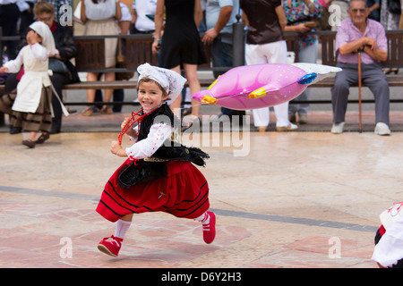 Spanish girl in traditional costume playing with balloon at annual fiesta at Villaviciosa in Asturias, Northern Spain Stock Photo