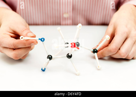 Hand of female student assembling amino acid molecule models for science project Stock Photo