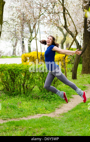 A happy young woman jumping in a park Stock Photo