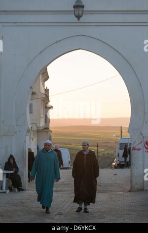 two traditionally dressed men walking through the town gate of Moulay Idriss Stock Photo