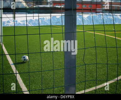 Soccer ball on field behind fence Stock Photo