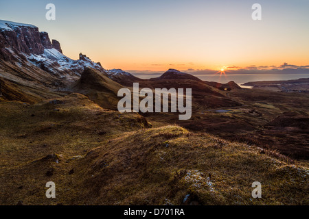 The morning sun rises over the Quiraing on Scotland's Isle of Skye bathing the prehistoric landscape in its morning glow. Stock Photo