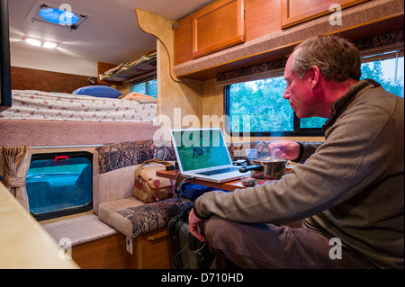 Professional photographer editing digital photographs on laptop computer inside a camper truck, Denali National Park, Alaska USA Stock Photo