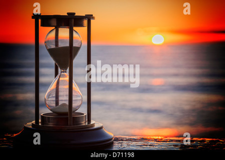 Sand Timer at Sunrise - Sand timer on a wooden ledge, looking out over a sunrise. Stock Photo