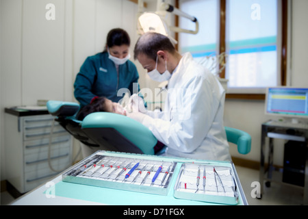 Close up of dental equipment in hospital with patient lying on couch and dentist working. Focus on foreground Stock Photo