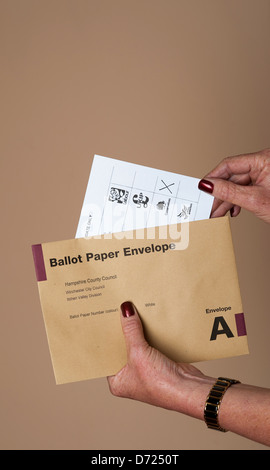 Ballot paper X against the Conservative party box Paper being placed in the postal vote envelope Stock Photo