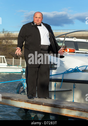 Overweight man in tuxedo standing on the deck of a luxury pleasure boat Stock Photo