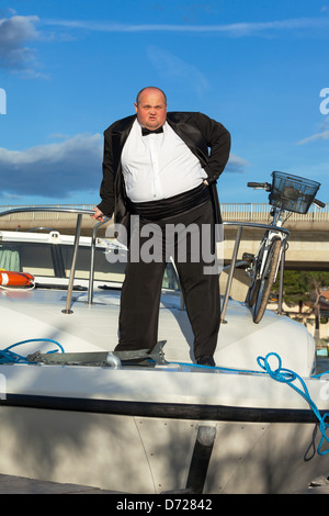 Overweight man in tuxedo standing on the deck of a luxury pleasure boat Stock Photo