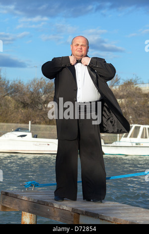 Overweight man in tuxedo standing on the pier marina Stock Photo