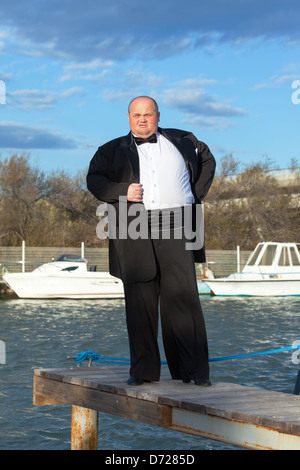 Overweight man in tuxedo standing on the pier marina Stock Photo