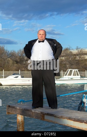 Overweight man in tuxedo standing on the pier marina Stock Photo