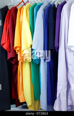 Colorful assortment of menswear shirts hanging from a clothes rack in a closet. Stock Photo