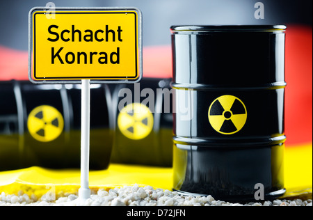 Three nuclear waste barrels before a Germany flag and local sign with label Shaft Konrad Stock Photo