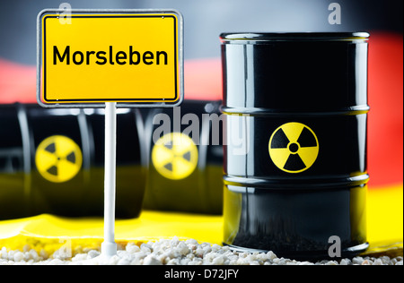 Three nuclear waste barrels before a Germany flag and local sign with label Morsleben Stock Photo