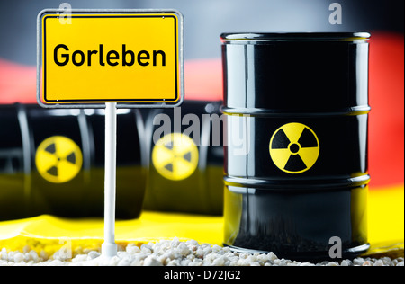 Three nuclear waste barrels before a Germany flag and local sign with label Gorleben Stock Photo