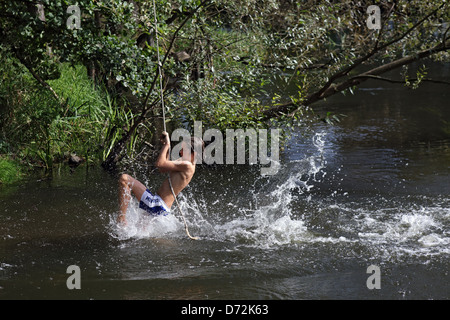 Briescht, Germany, boy swinging on a rope over the river Spree Stock Photo