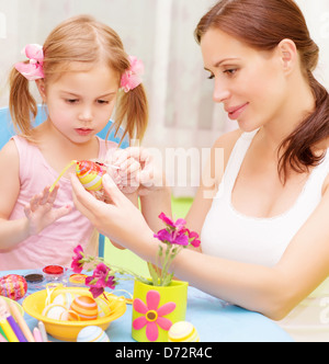 Closeup portrait of cute little baby girl with beautiful young mother paint Easter eggs, traditional Christian symbol Stock Photo