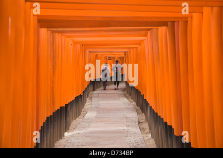 Tourist walking through the columned stairway, Fushimi Inari shrine, Kyoto, Japan Stock Photo