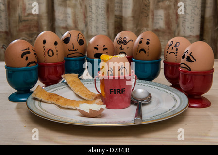 Eggsercution 8 eggs looking on as boiled egg has his head chopped off Stock Photo