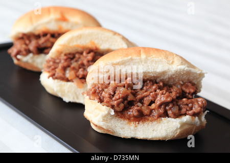 Three home-made Sloppy Joe slider sandwiches on a black serving tray. Stock Photo