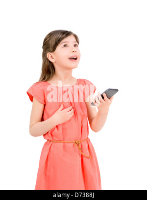 Inspired cute little girl in red dress looking up and holding in her hand mobile phone. Isolated on white background. Stock Photo