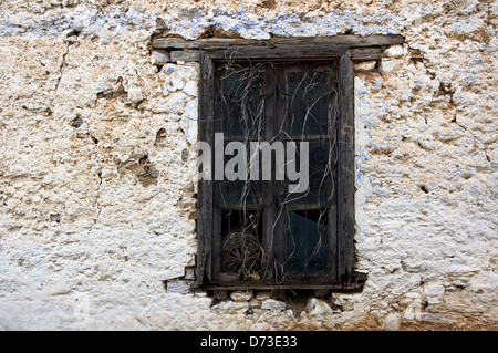 Old window with ornate iron grille in weathered stone house front Stock Photo