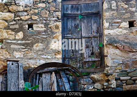 Ramshackle wooden door in old stone house front (Greece) Stock Photo