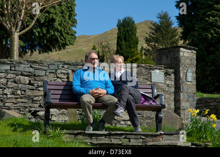 Middle-aged couple relaxing on a bench in Ambleside, Lake District National Park, Cumbria, England UK Stock Photo