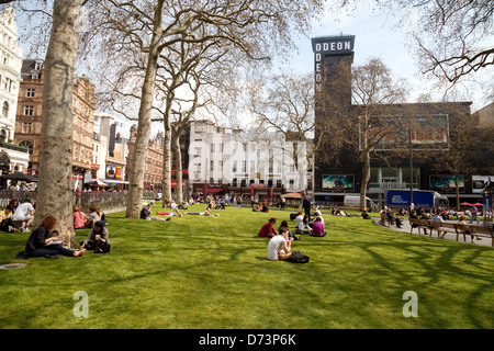 People sitting on the grass on a sunny day, Leicester Square Central London WC2, UK Stock Photo