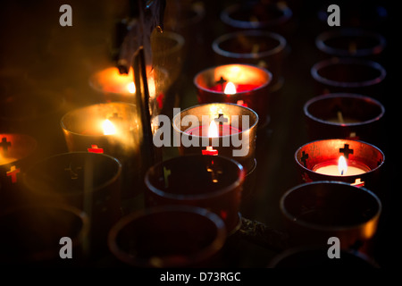 Devotional candles lighting a darkened Roman Catholic Basilica of the National Shrine of Mary, Queen of the Universe. Stock Photo